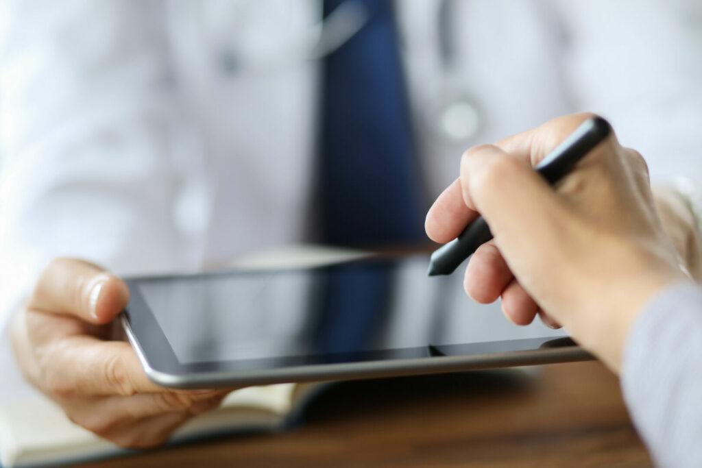 photo : Advanced technology in the modern hospital. Patient puts an electronic signature on a health insurance contract using a tablet pc.