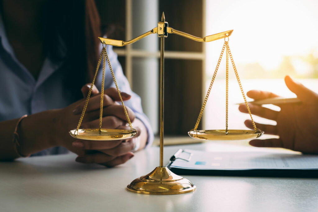 photo : Business woman and lawyers discussing contract papers with brass scale on wooden desk in office. Law, legal services, advice, Justice and real estate concept.