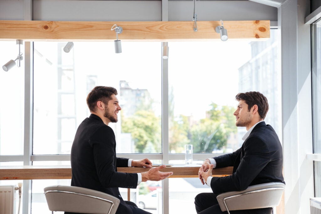 photo : Two cheerful young businessmen having business meeting