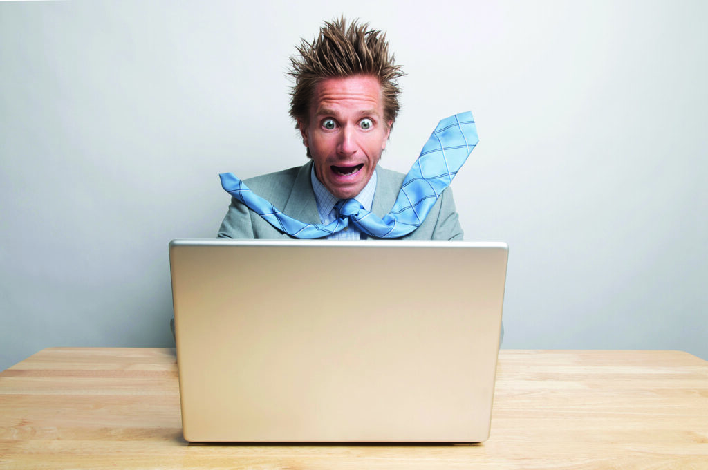 photo : Surprised office worker freaking way out looking at his computer