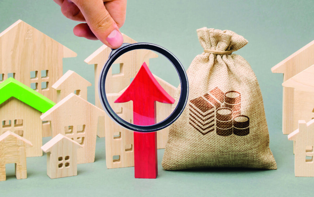 photo : Red arrow up, money bag and miniature wooden houses. The concept of rising property prices. High mortgage rates. Expensive rental apartment. Growing demand for home purchase. Real estate market.