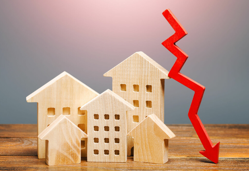 photo : Real estate houses and a red arrow down. Lower mortgage interest rates. Falling prices for rental apartments. Low demand for home buying. Market recession. Low liquidity, investment unattractiveness.